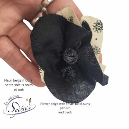 fleur décorative sur épinglette noire et beige motif de soleils noir