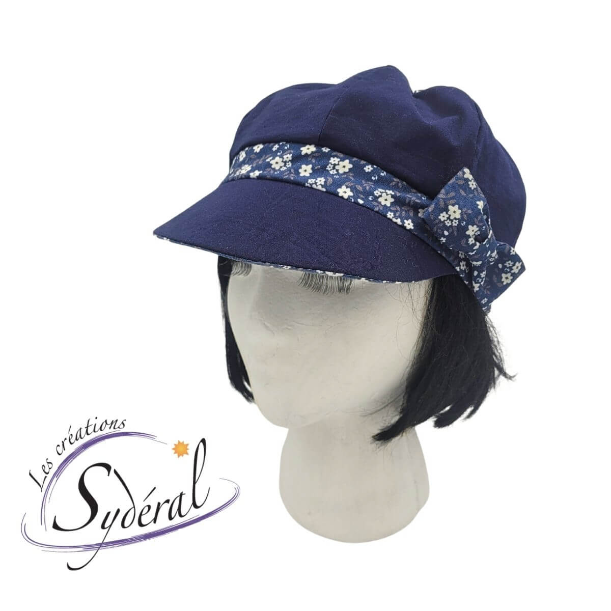 casquette d'été en coton pour femme. Marine avec bande de tour de tête et dessous de la palette bleu à motifs de petites fleurs blanche, vue de 3/4