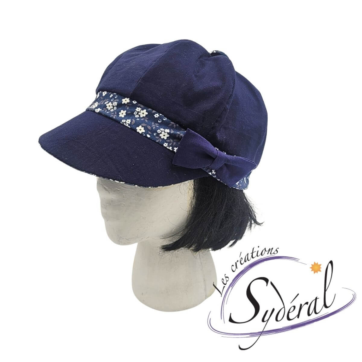 casquette d'été en coton pour femme. Marine avec bande de tour de tête et dessous de la palette bleu à motifs de petites fleurs blanche, vue de 3/4